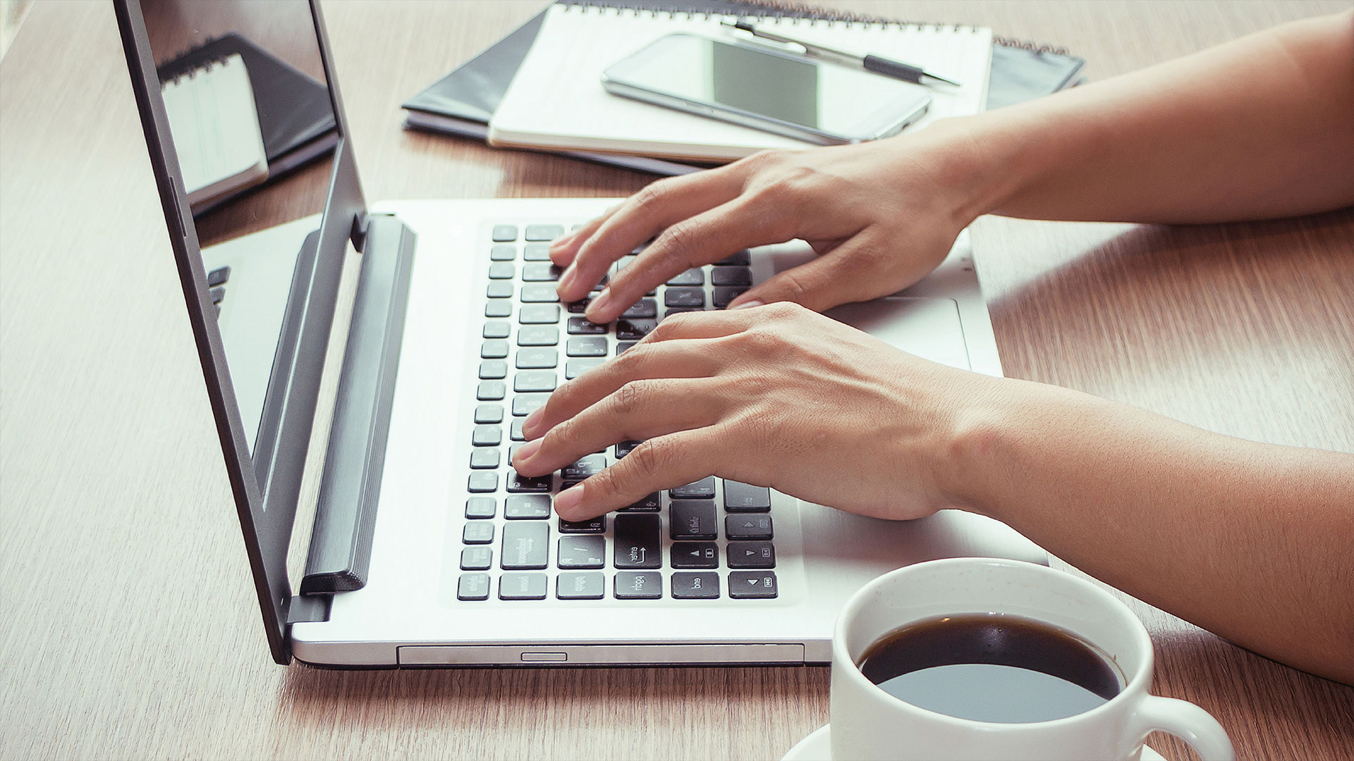 Hands typing on a laptop keyboard